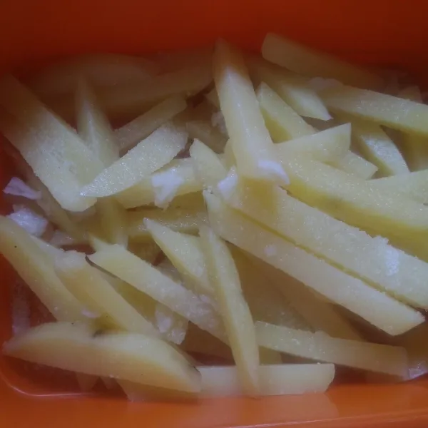 Tiriskan kentang, taburi dengan kaldu bubuk dan aduk hingga rata.