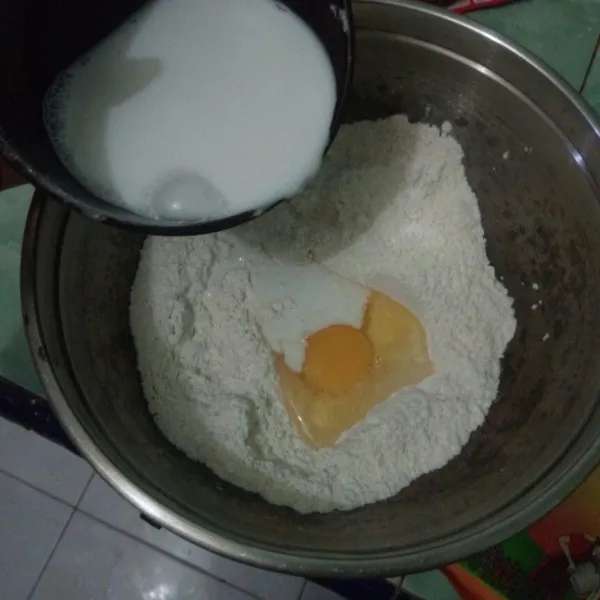 Tambahkan telur, air dan santan yang telah dimasak ke dalam adonan tepung sedikit demi sedikit.