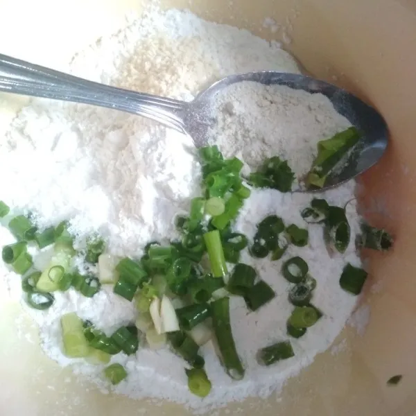 Campurkan tepung terigu, tepung tapioka, daun bawang, garam, dan kaldu jamur. Aduk dengan menggunakan sendok