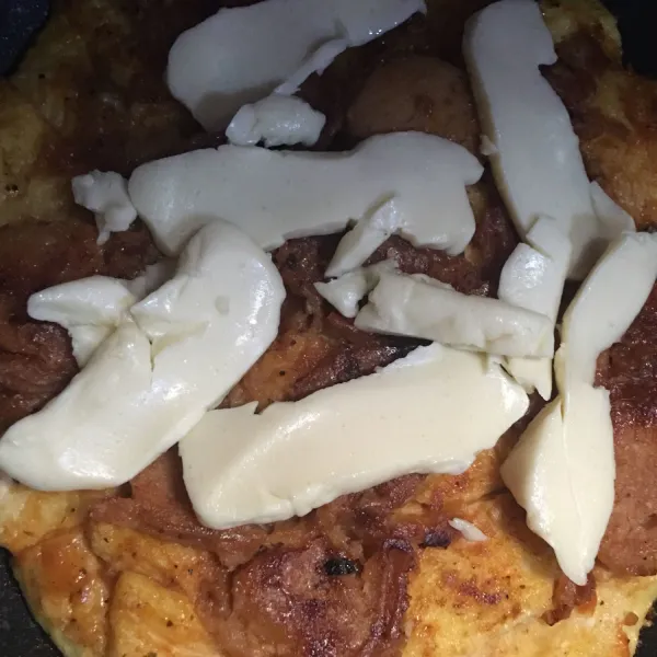 Balikkan kembali pizza lalu taburkan keju quick melt sesuai selera, dan tutup dengan penutup wajan. Diamkan beberapa saat hingga keju meleleh.