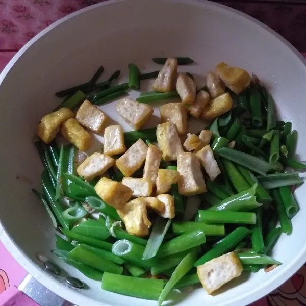 Masukkan kembang bawang, tumis hingga layu. Kemudian masukan tahu, garam, dan gula. Masak sebentar hingga semua tercampur merata.