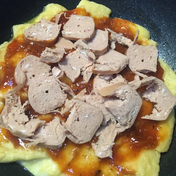 Masukkan campuran roti dan telur ke dalam wajan, lalu oleskan saus barbeque sesuai selera. Kemudian saus bolognese sesuai selera lalu taburkan potongan sosis di atasnya, dan masak di atas kompor dengan api kecil.