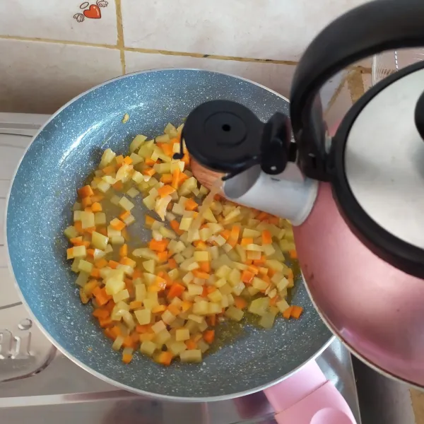 Masukkan kentang dan wortel. Lalu tambahkan air. Masak hingga sayuran empuk.