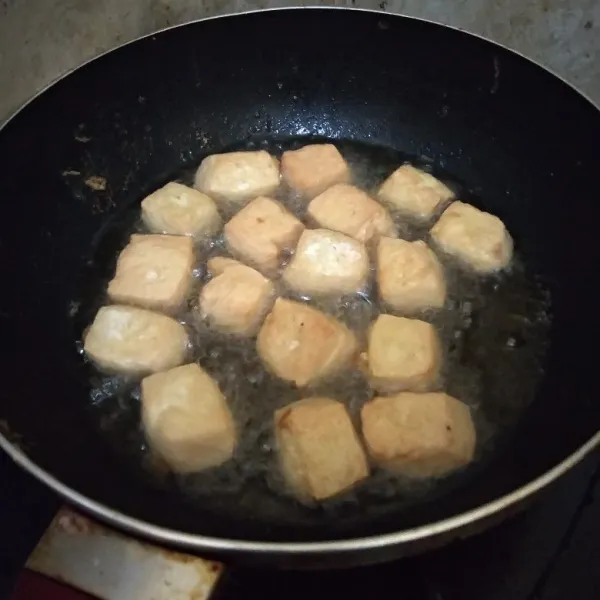 Panaskan minyak, goreng tahu hingga kecoklatan. Lalu tuang 1 sendok sayur adonan tepung. Tunggu hingga kering.