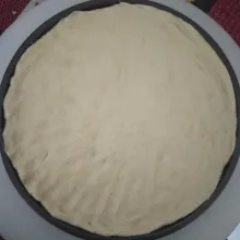 kempeskan adonan sebelum dipindahkan ke loyang pizza. Ratakan di loyang pizza dan diamkan selama 5 menit.