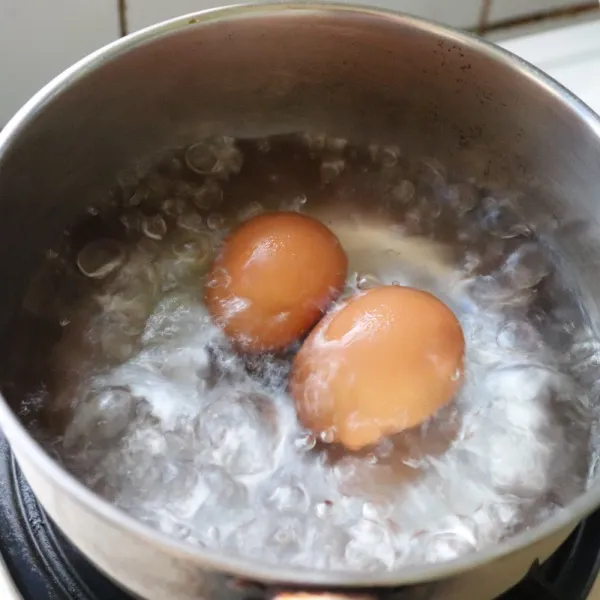 Rebus telur ke dalam air mendidih selama 7 menit, angkat dan kupas kulitnya.