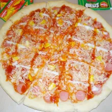 Tusuk adonan menggunakan garpu. Kemudian oleskan campuran saus tomat dan sambal di atasnya, parutan keju, serta susun semua toppingnya. Panggang di oven pemanasan atas bawah 175°C selama 18 menit. Percantik pizza dengan saus sambal dan mayones di atas kemudian panggang lagi di oven selama 5 menit. Pizza siap dinikmati.