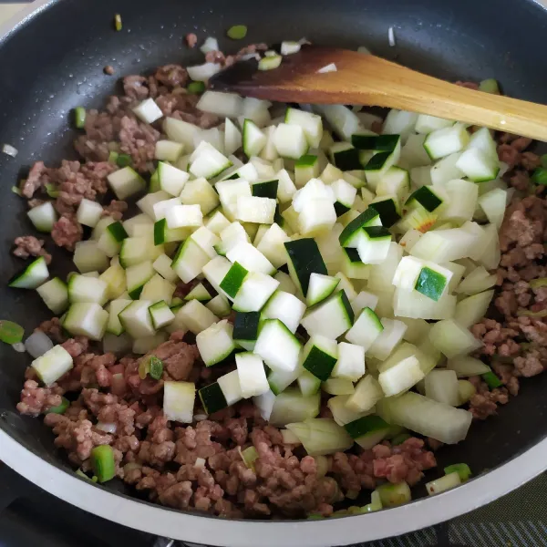 Masukkan potongan zucchini dan bawang bombay.
