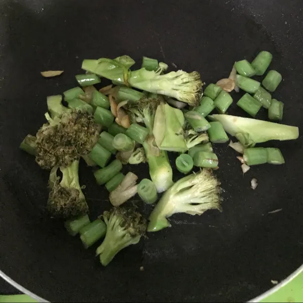 Potong brokoli ambil kuntumnya saja, kemudian potong buncis. Lalu tumis dengan bawang putih dan minyak wijen hingga harum.