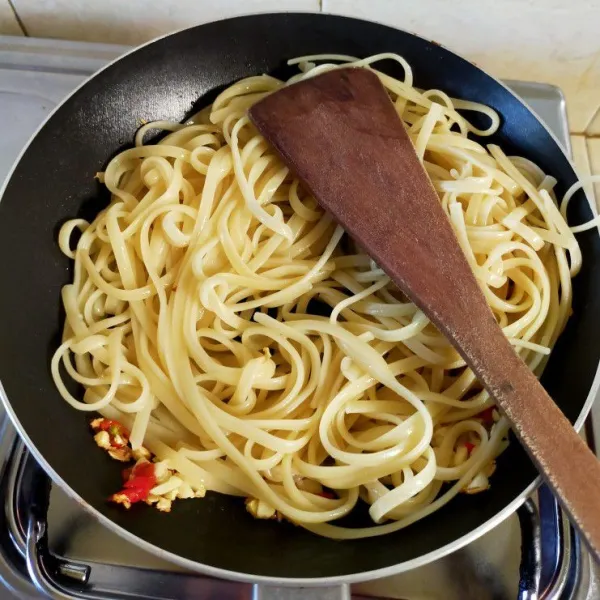 Masukkan mie pipih. Tambahkan cabe bubuk, garam, lada, irisan daun kemangi, dan sosis. Aduk hingga rata.