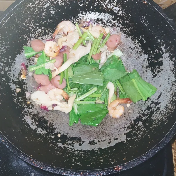 Tumis bumbu cincang sampai harum lalu masukkan udang dan sosis, tunggu sampai udang berubah warna lalu masukkan sedikit air lalu masukkan sawi serta jamur, aduk rata.