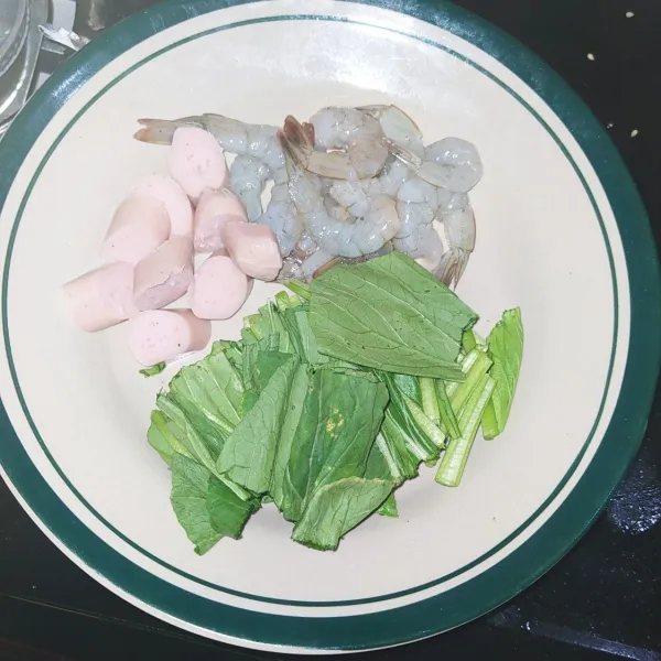 Potong sosis dan sawi serta kupas udang, buang kulitnya.