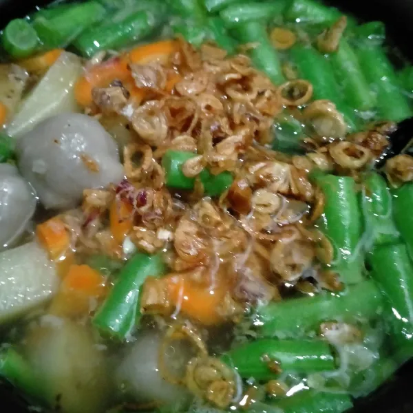 Masukkan buncis, pentol, garam dan kaldu bubuk. Masak hingga sayuran matang, masukkan bawang goreng. Tes rasa, angkat.