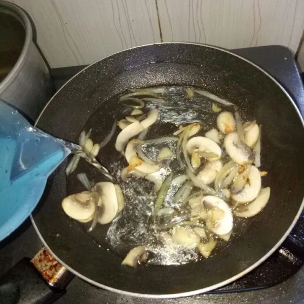 Siapkan pan dan panaskan minyak. Tumis bawang putih dan bawang bombay sampai harum, masukkan jamur. Aduk rata, tumis sampai jamur keluar kaldu lalu tambahkan air. Masak sampai air mendidih.