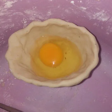 Ambil adonan, buat lengkungan, lalu masukan telur. Tutup atas adonan sampai rekat dengan cara di tekan oleh jari
