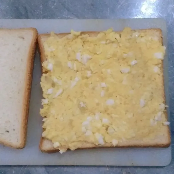 Siapkan 1 lembar roti tawar dan oleskan campuran telur kentang di atasnya, tutup dengan lembar roti tawar lain.