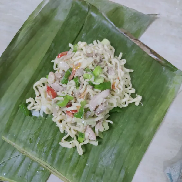 Siapkan 2 lembar daun pisang, masukkan mie kemudian bungkus rapi.