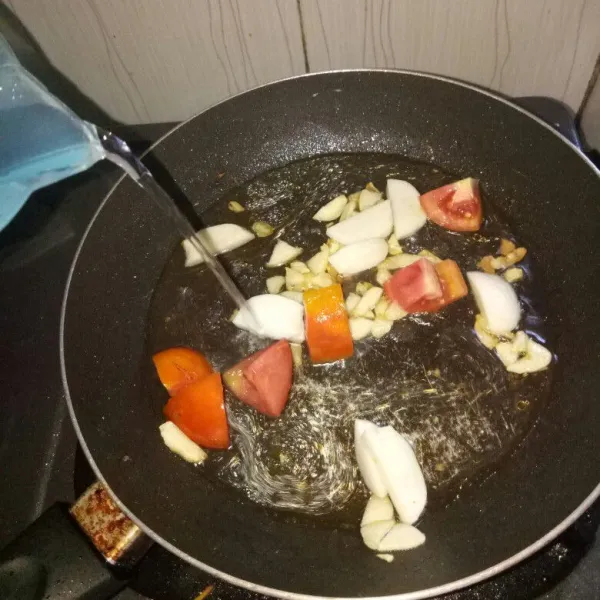 Siapkan pan dan panaskan minyak. Tumis bawang putih sampai harum, masukkan tomat. Aduk sampai tomat layu, tambahkan air, aduk rata.