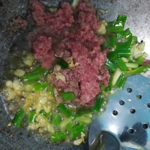 Masukkan daging giling dan daun bawang, aduk hingga berubah warna.