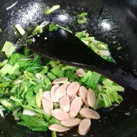 Masukkan sawi dan sosis aduk rata. Beri air, masak hingga sawi matang.