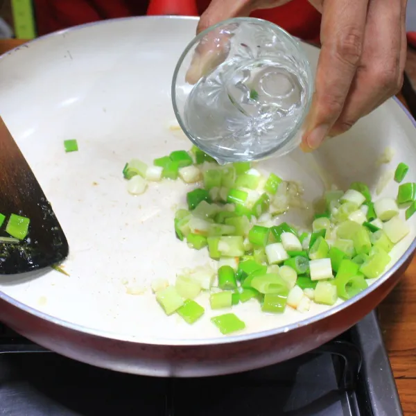 Tumis bawang putih dan daun bawang sampai layu, kemudian tambahkan air