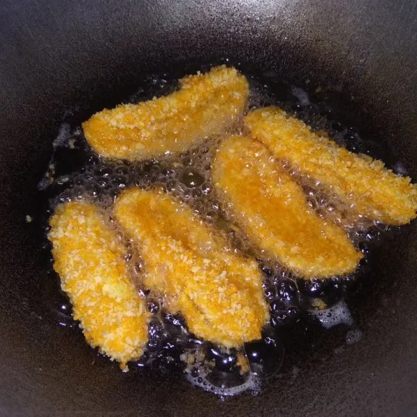 Panaskan minyak goreng. Lalu goreng pisang nugget dengan api sedang supaya tidak cepat gosong sampai berwarna kuning kecoklatan, angkat dan tiriskan.