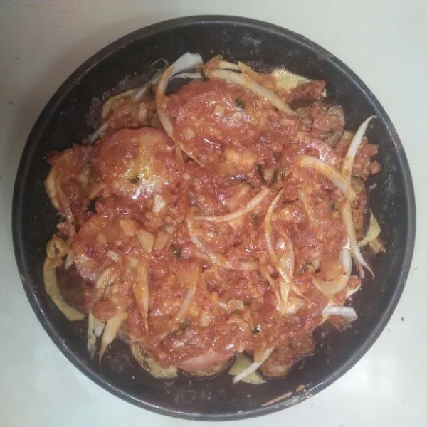 Letakan potongan tomat dan irisan bawang bombay lalu siram kembali sisa saus dagingnya sampai rata.