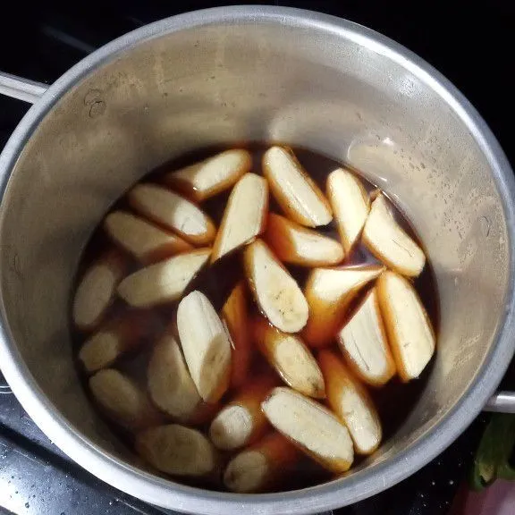 Pindahkan ke panci yang lebih besar, tambahkan sisa air, kemudian masukkan pisang, masak hingga mendidih dan pisang berubah warna.