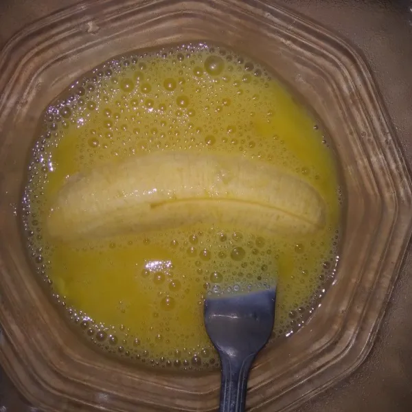 Kocok lepas telur dan garam, lalu celupkan pisang ke dalam telur.