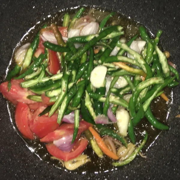 Setelah ikan masak, tumis cabe hijau, bawang merah, bawang putih, dan tomat yang telah diiris ke minyak bekas ikan. Lalu tambahkan garam sejumput, kaldu jamur, dan saus tiram. Masak hingga tomat layu dengan api sedang.