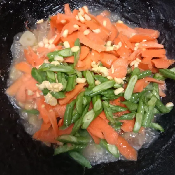 Masukkan kacang panjang, wortel, dan jagung manis lalu ratakan dan masak sampai matang.