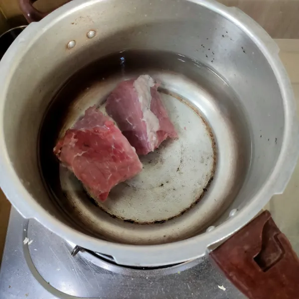 Cuci bersih daging sapi, kemudian masukkan dalam panci presto, tambahkan air,   tutup panci, lalu rebus selama 15 menit, angkat. Air rebusan jangan dibuang, akan dipakai pada proses berikutnya.