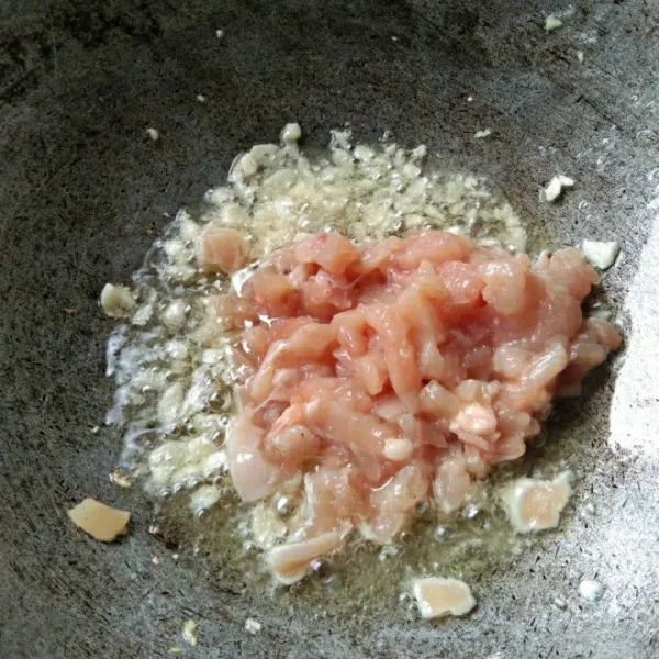 Tumis bawang putih hingga harum, masukan cacahan daging ayam, masak hingga berubah warna.