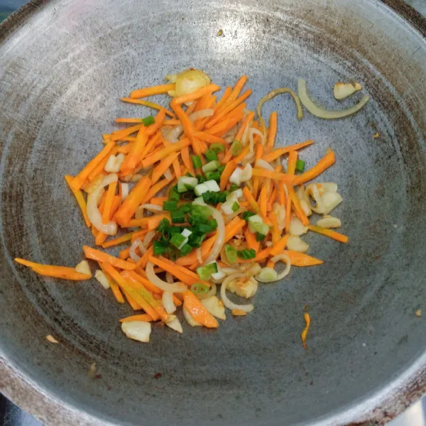 Masukkan wortel dan daun bawang. Aduk rata. Masak sampai wortel layu.