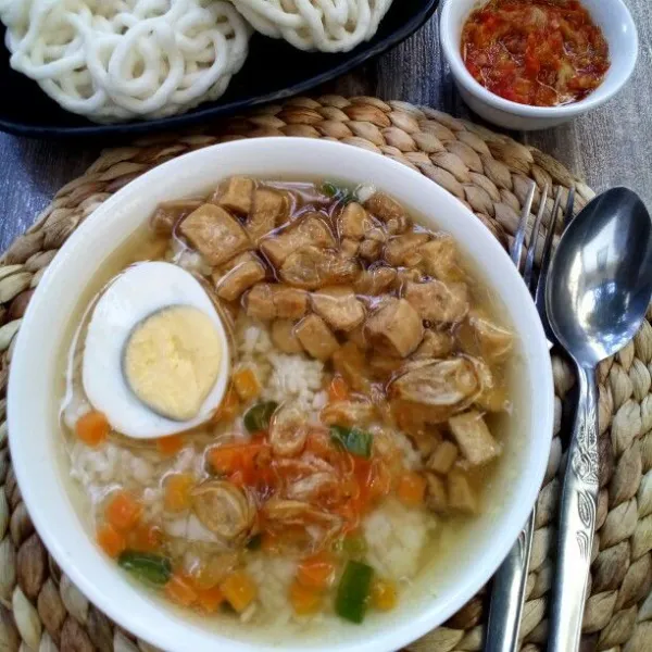 Sajikan nasi bersama tumisan ayam tahu dengan kuah dan pelengkap.