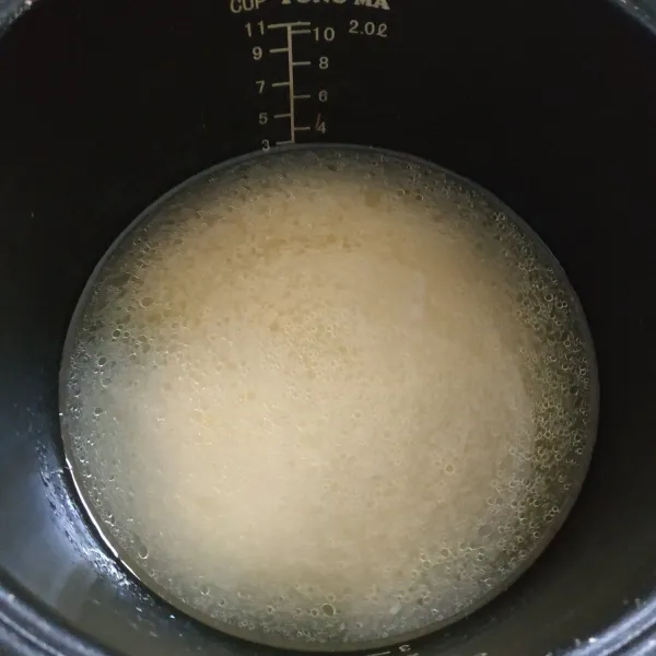 Campurkan nasi, air kaldu rebusan ayam, garam, dan tumisan bawang putih jahe. Masak nasi dengan rice cooker hingga matang.