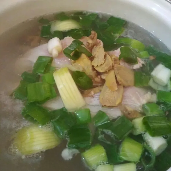 Didihkan air masukkan potongan daun bawang, irisan jahe, potongan Bombay tambahkan fillet ayam masak hingga ayam.