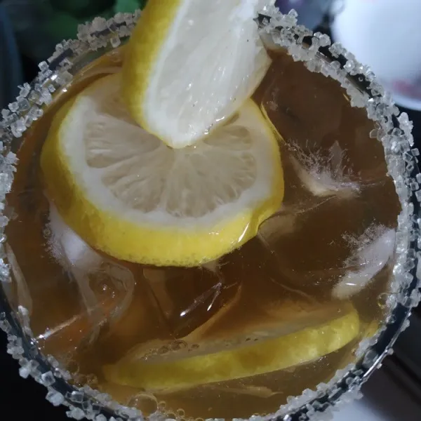 Tambahkan es batu ke dalam gelas saji lalu beri irisan lemon dan tuang teh.