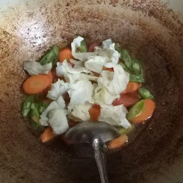 Masukkan sayuran, tambahkan air. Aduk rata. Masak hingga sayuran setengah matang.