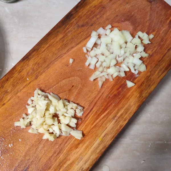 Membuat saus: cincang bawang bombay dan bawang putih.
