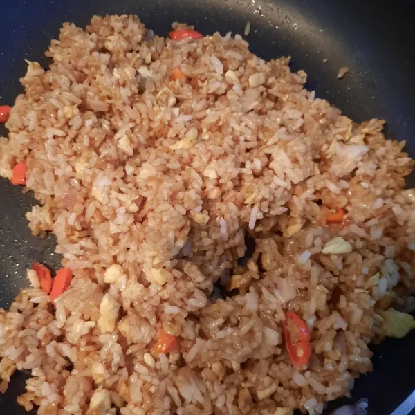 Masak terus sambil diaduk hingga nasi agak kering kemudian koreksi rasa. Angkat dan sajikan nasi goreng.