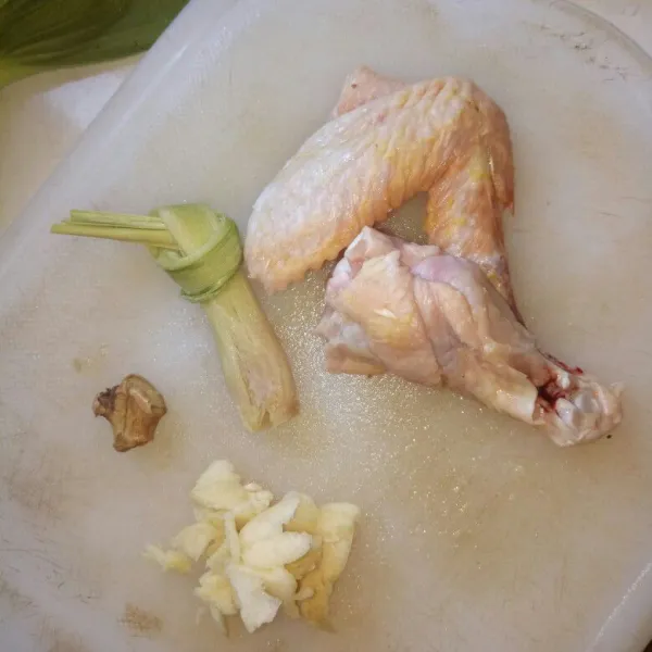 Cuci bersih ayam, potong menjadi beberapa bagian. Iris bawang putih, geprek jahe dan serai.