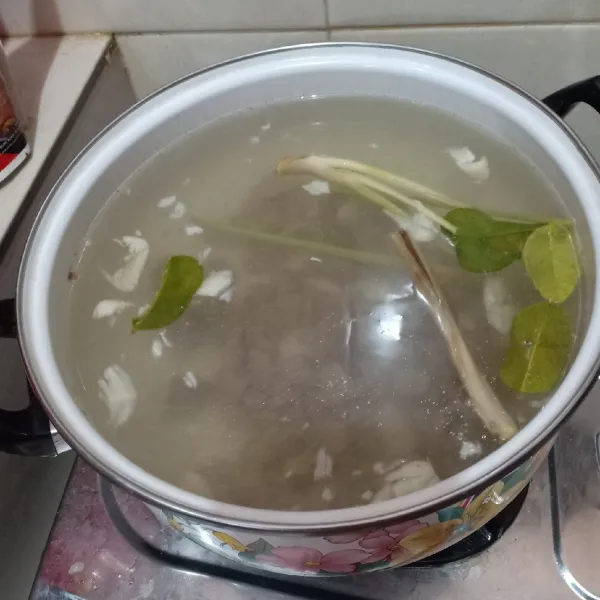 Didihkan air lalu rebus kembali daging hingga empuk, minimal selama 30 menit. Tambahkan serai geprek, daun jeruk dan bawang putih geprek.