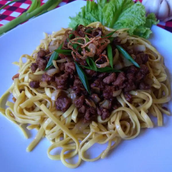 Tambahkan tumis daging sapi cincang, selada, daun bawang dan bawang goreng di atas mie. Sajikan.