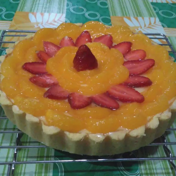 Angkat dan beri topping buah mandarin & strawberry. Olesi bagian atas buah dengan jelly plain. Sajikan dingin.