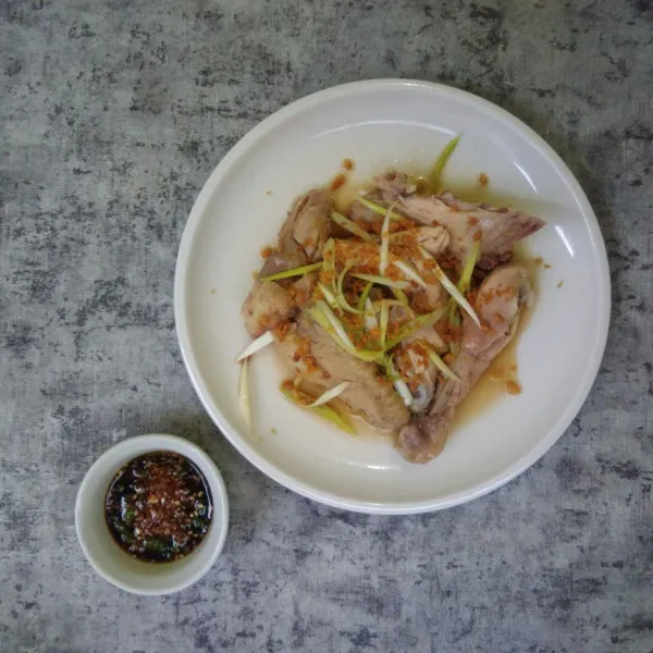 Tata ayam dalam piring, beri taburan bawang outih dan daun bawang. Sajikan bersama sambal kecap dan nasi hainan.