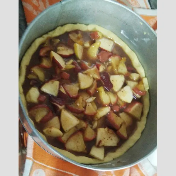 Setelah Dough Pie setengah matang, masukkan Bahan Filling Apple Pie dan tutup permukaan filling dengan sisa Dough Pie. Oleskan kocokan kuning telur dipermukaan atasnya secara supaya terlihat lebih cantik. Buat garis tanda X ditengah permukaan atas agar Dough tidak mengembung tinggi. Panggang selama 30 menit atau sampai terlihat kuning cokelat keemasan.