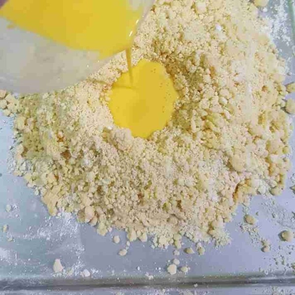 Campurkan kuning telur dan air es, tuangkan kedalam adonan campuran tepung. Uleni sebentar hingga tercampur rata.