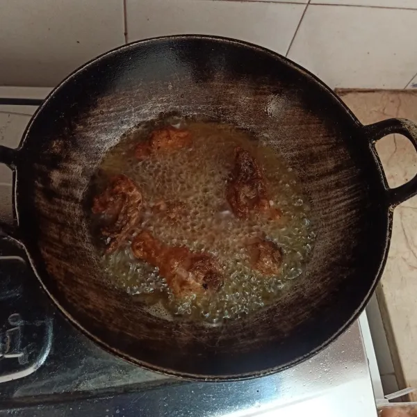 Goreng ayam yang sudah termarinasi dengan minyak panas sampai berubah warna, lalu angkat.