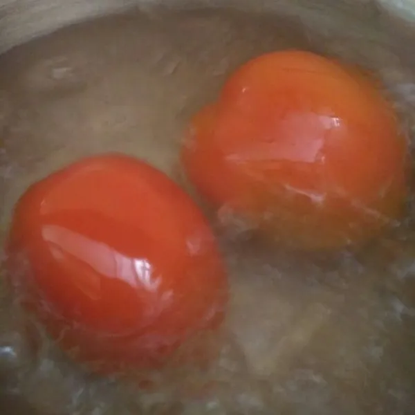 Rebus tomat hingga berkulit, angkat dan rendam air dingin, kemudian kupas kulitnya dan haluskan bersama cabai merah